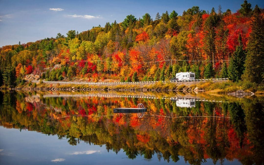 A lake surrounded by trees with autumn leaves reflected in the water.