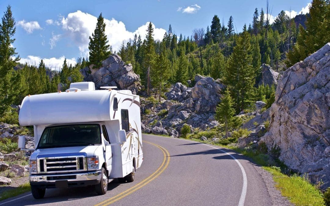 A white rv is driving down a curvy mountain road.