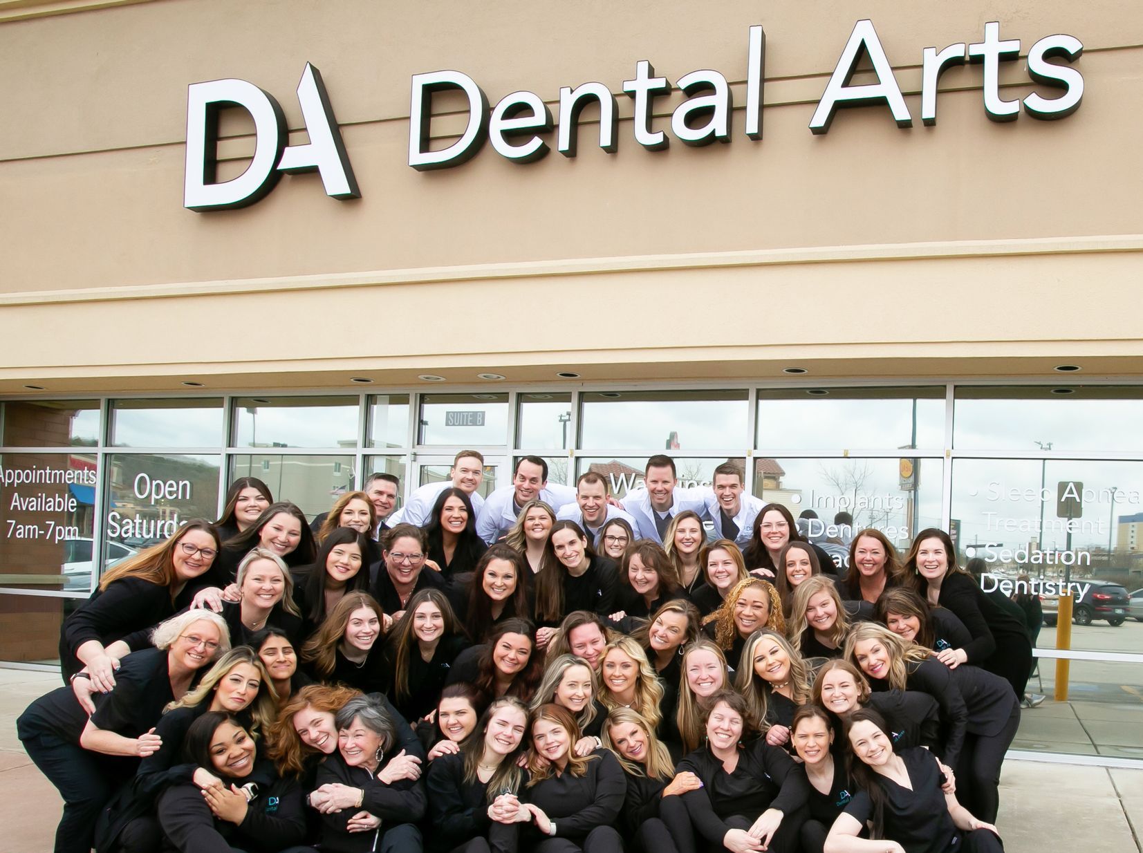 A group of people are posing for a picture in front of the da dental arts building