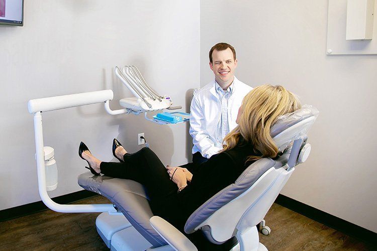 A woman is sitting in a dental chair talking to a dentist.