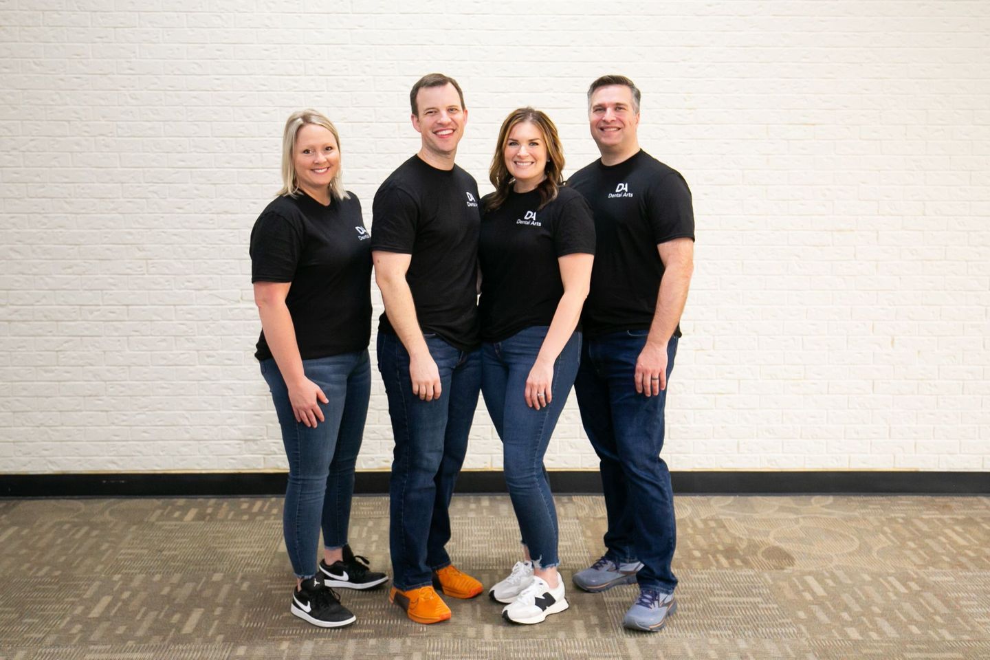 A group of people standing next to each other in front of a white brick wall.