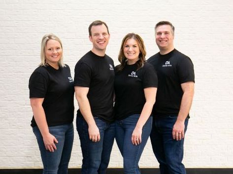 A group of people standing next to each other in front of a white brick wall.