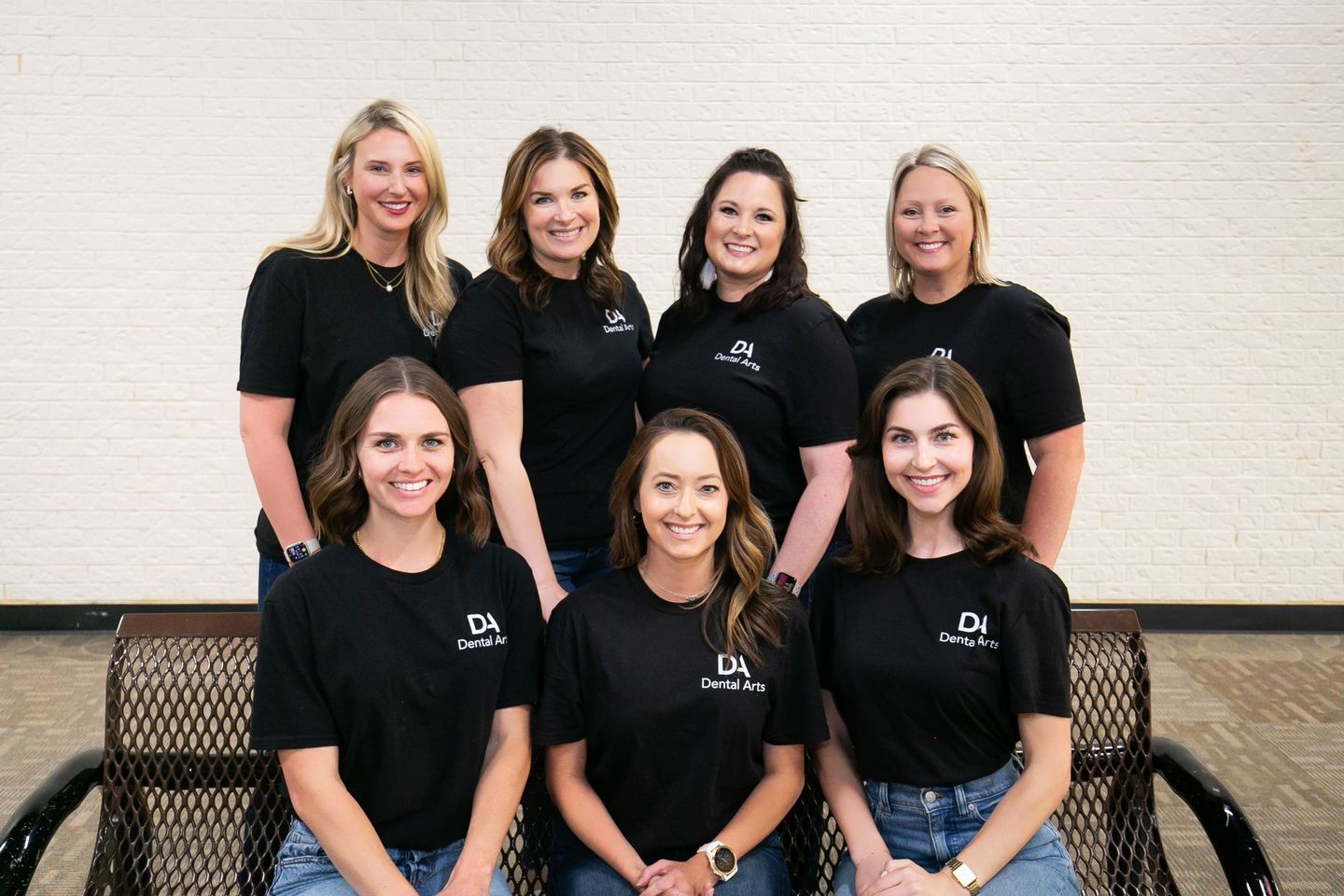 A group of women are posing for a picture while sitting on a bench.