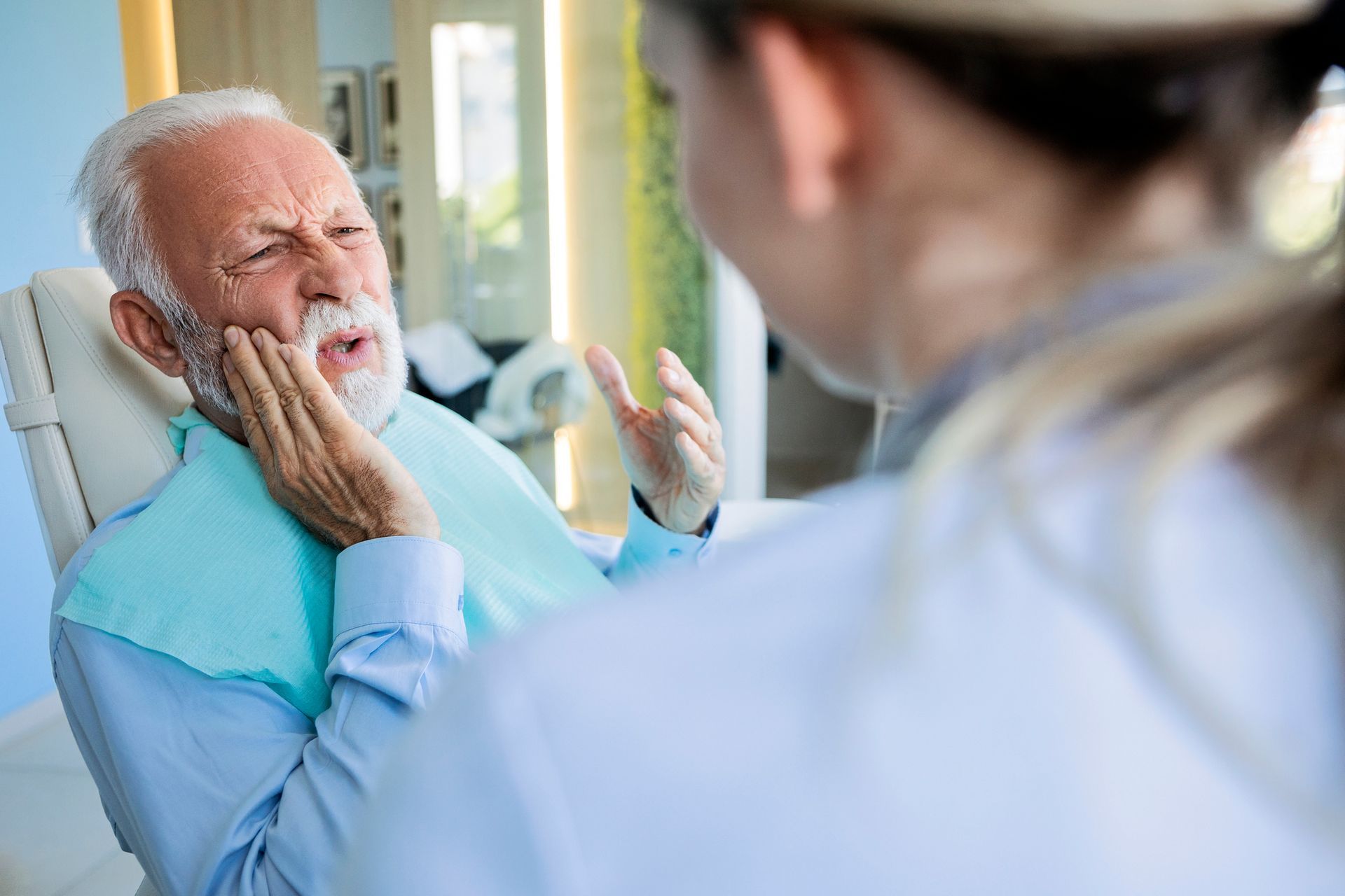 An elderly man is sitting in a dental chair with a toothache.