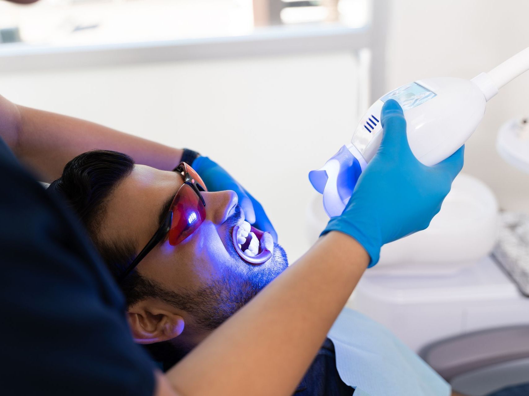 A man is getting his teeth whitened by a dentist.