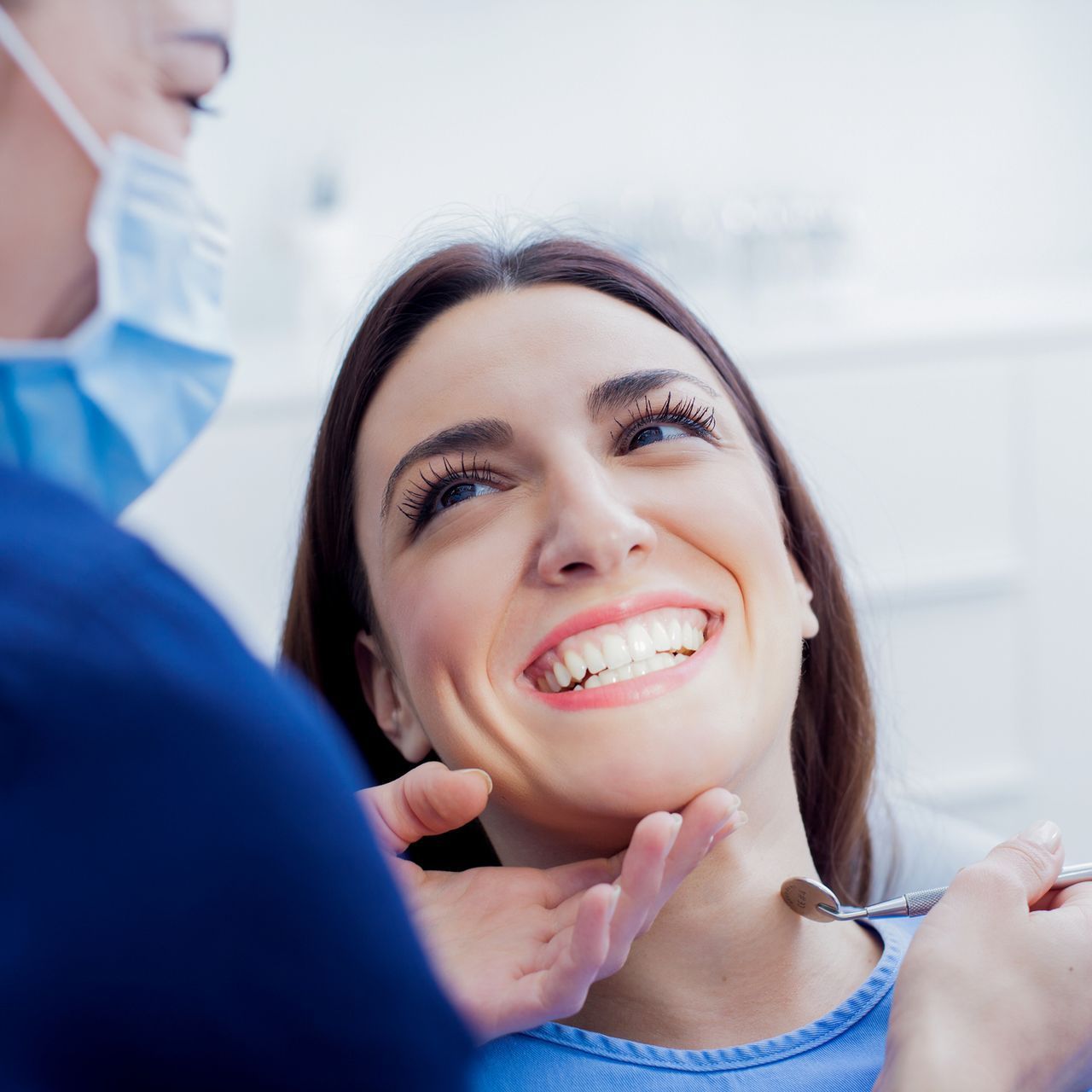 A woman is smiling while having her teeth examined by a dentist