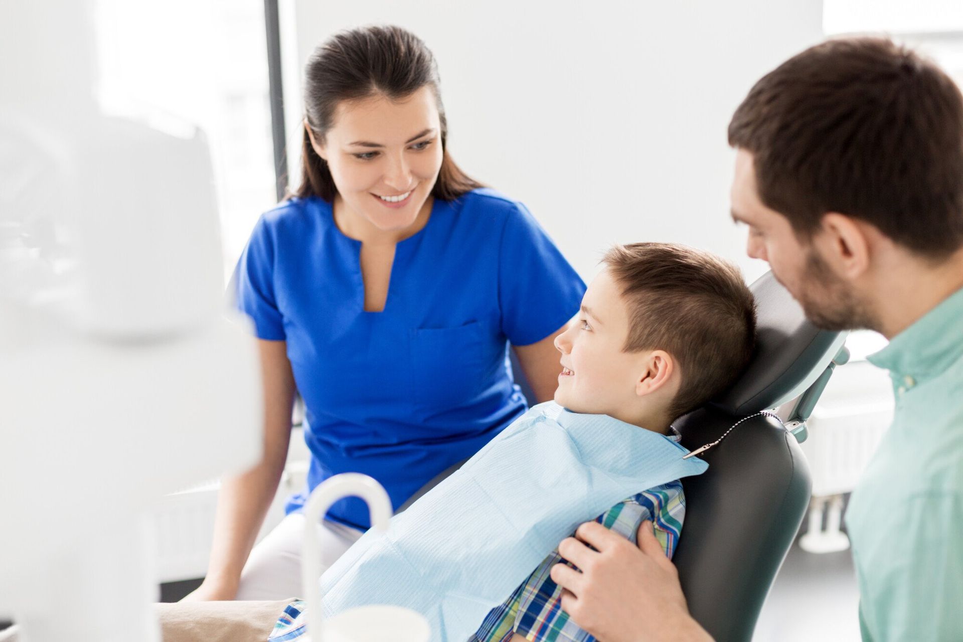 a young boy is sitting in a dental chair with the dental assistant