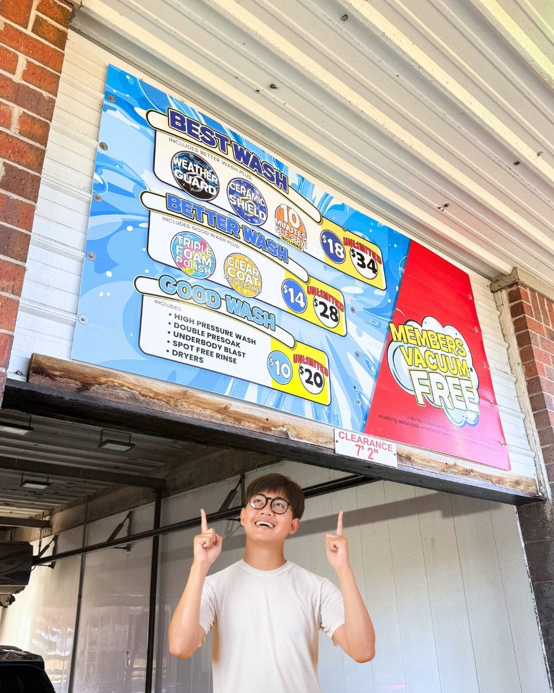A young man is standing in front of a Bubble town car wash.