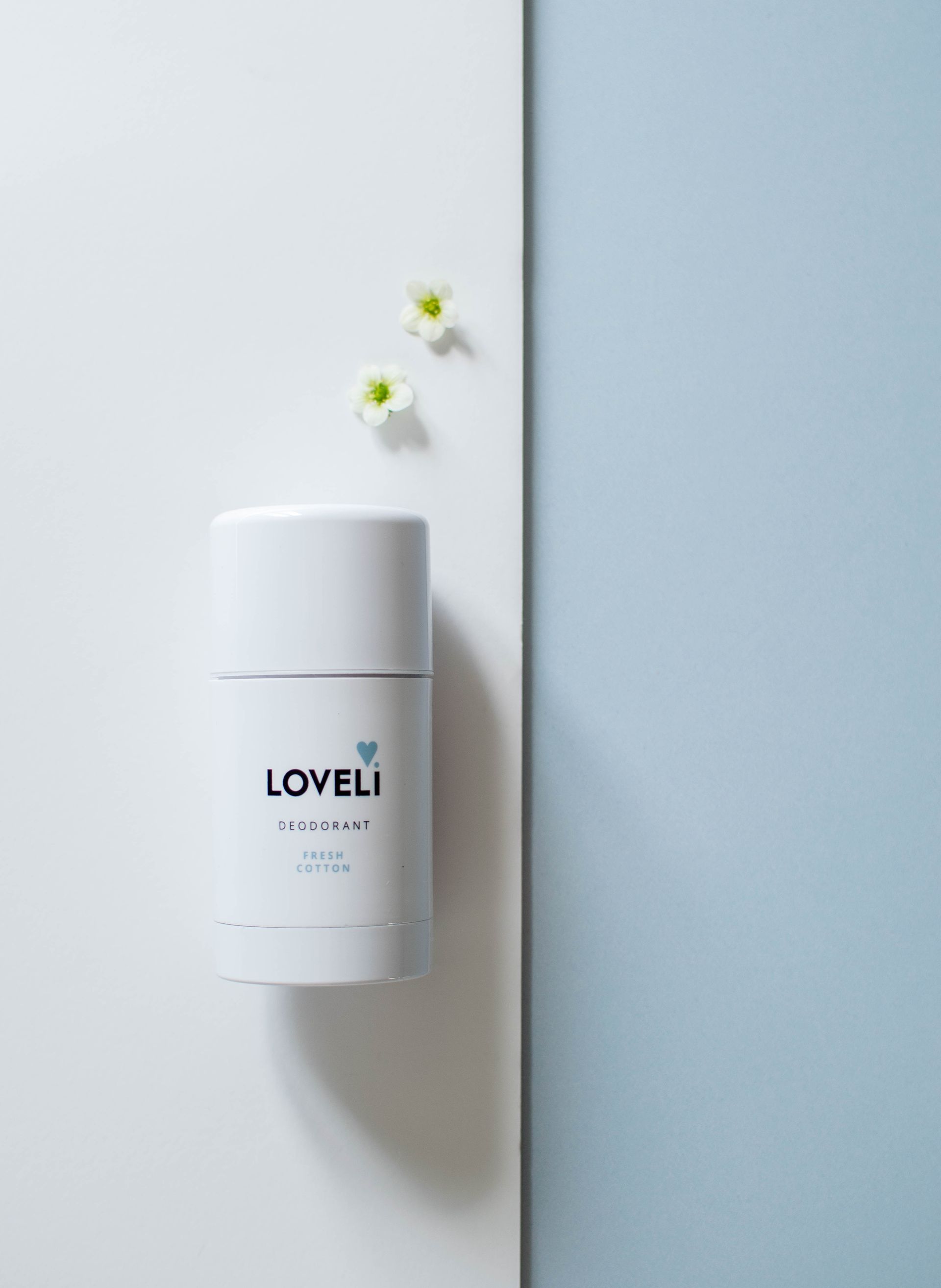 Een fles Loveli-deodorant staat op een wit oppervlak.