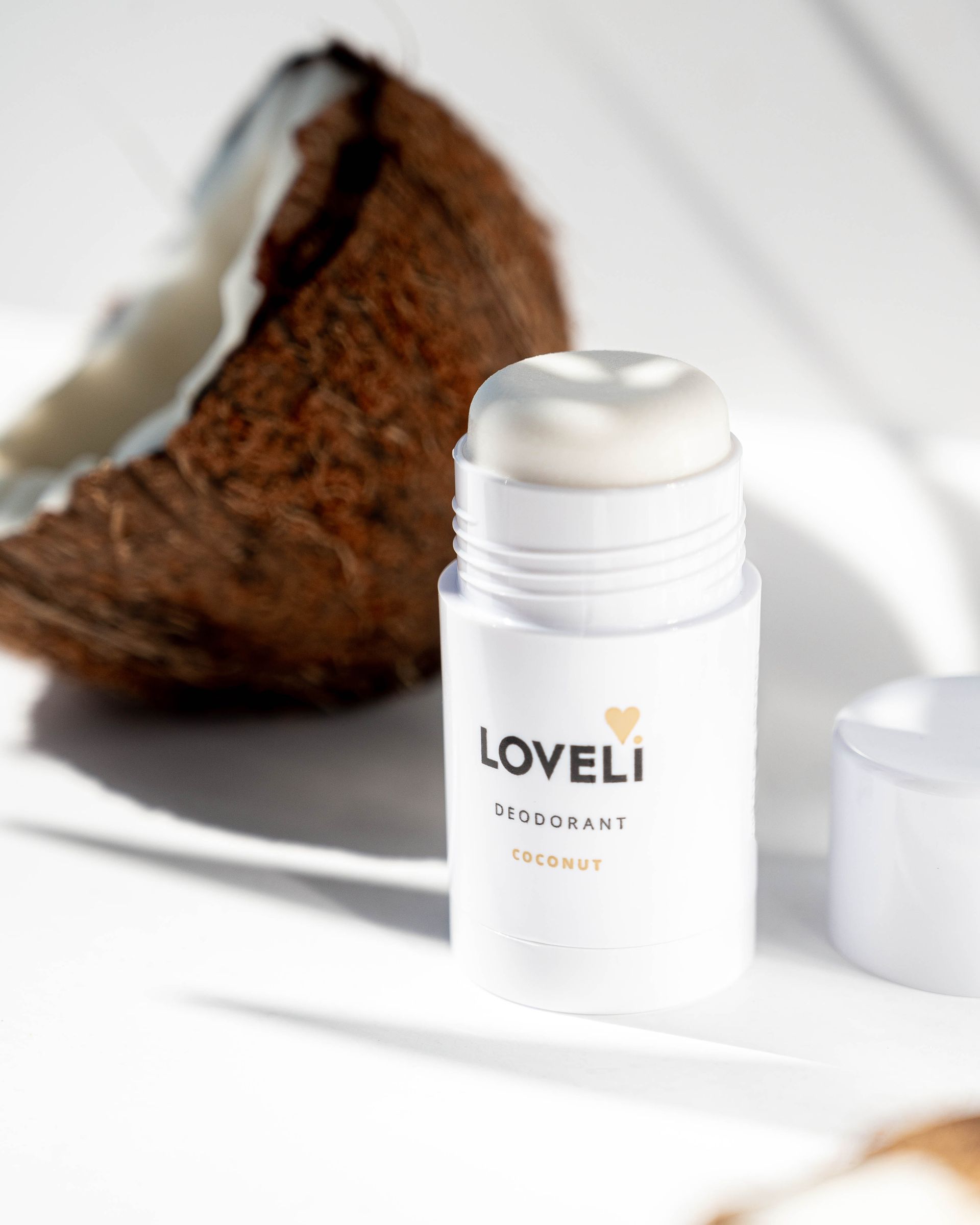 Een fles loveli deodorant naast een kokosnoot