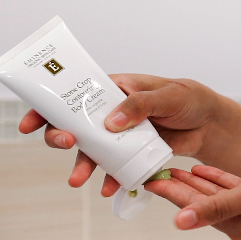 Een persoon houdt een tube Stone Crop contouring body cream vast