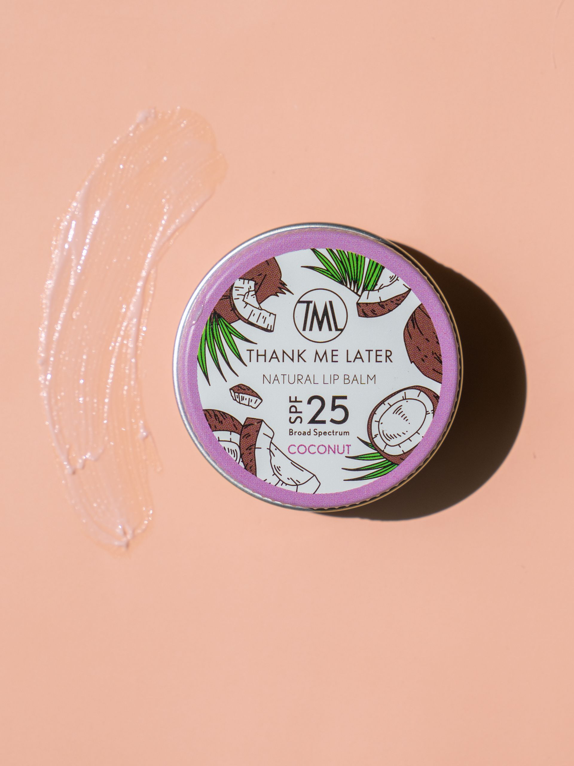 Een paars blikje lippenbalsem staat op een roze oppervlak.