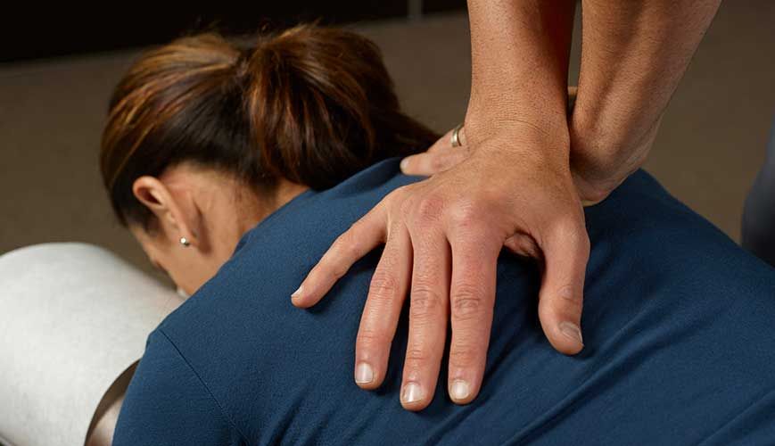 A man is examining a woman 's back while she sits on a table.