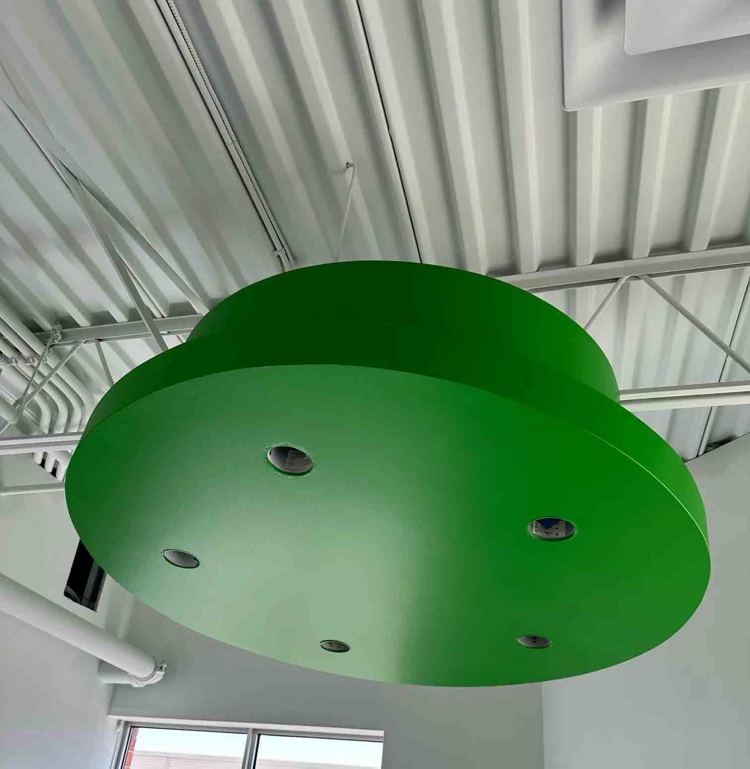 Plafonnier circulaire vert avec petits spots encastrés dans un intérieur de style industriel.