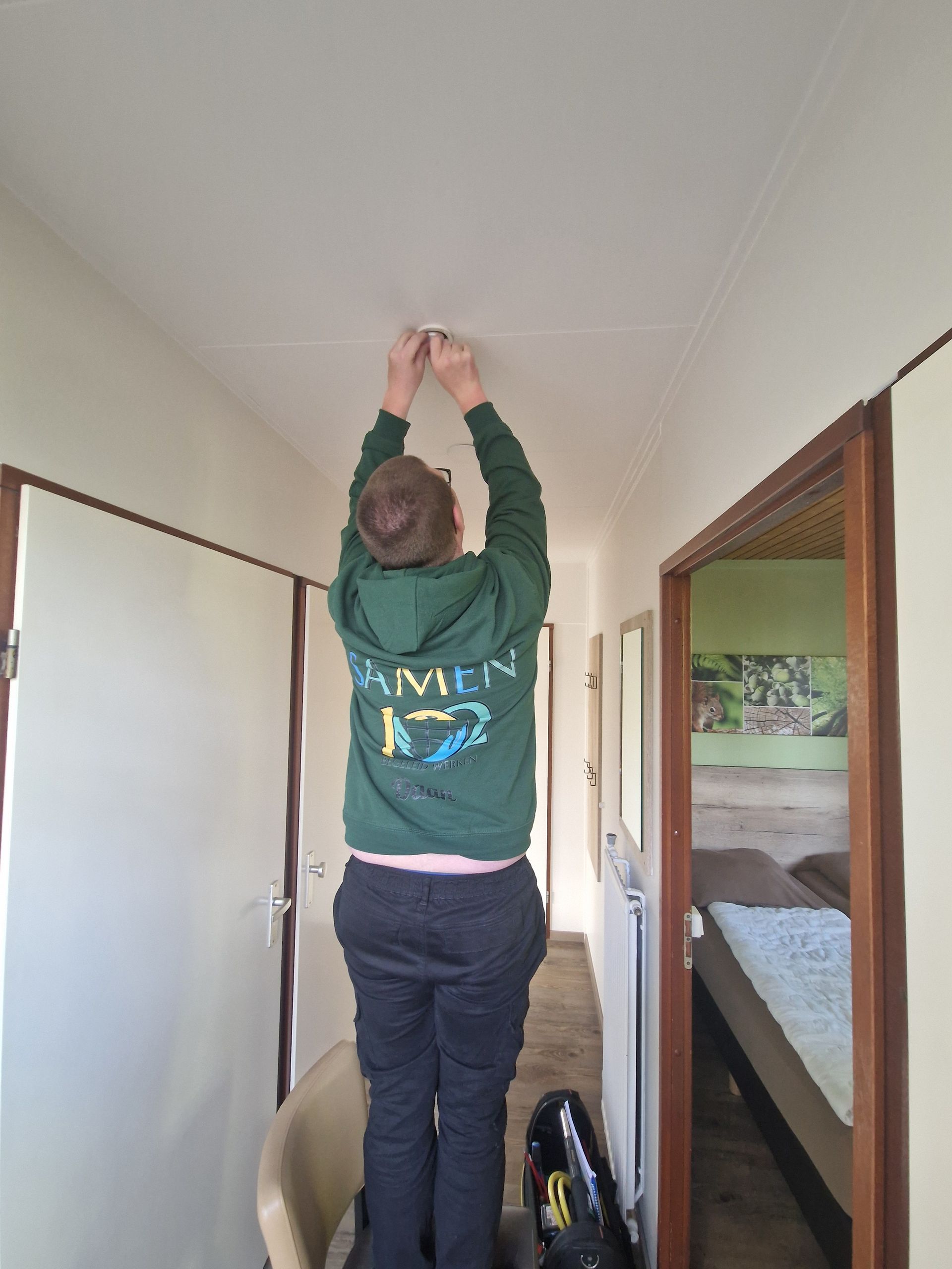 Een persoon die een groene hoodie draagt ​​met Samen102 erop