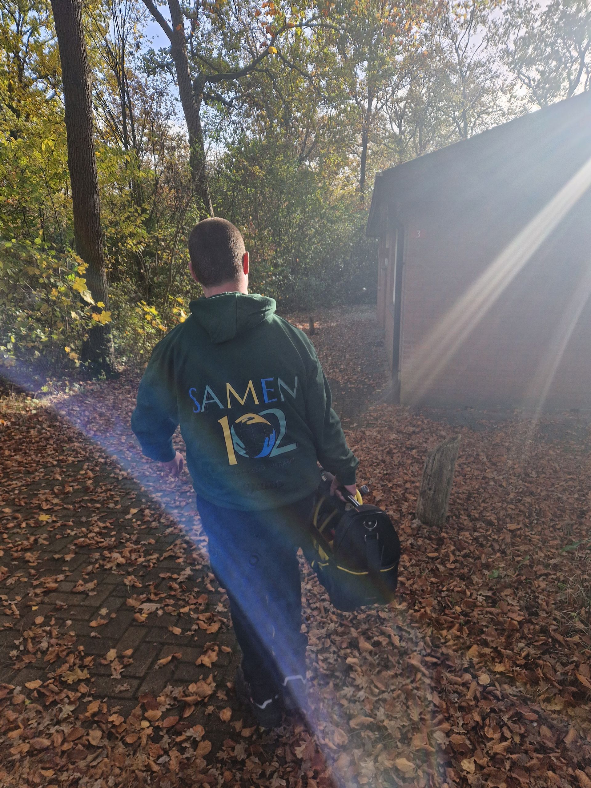 Een man in een groene hoodie loopt door het bos.