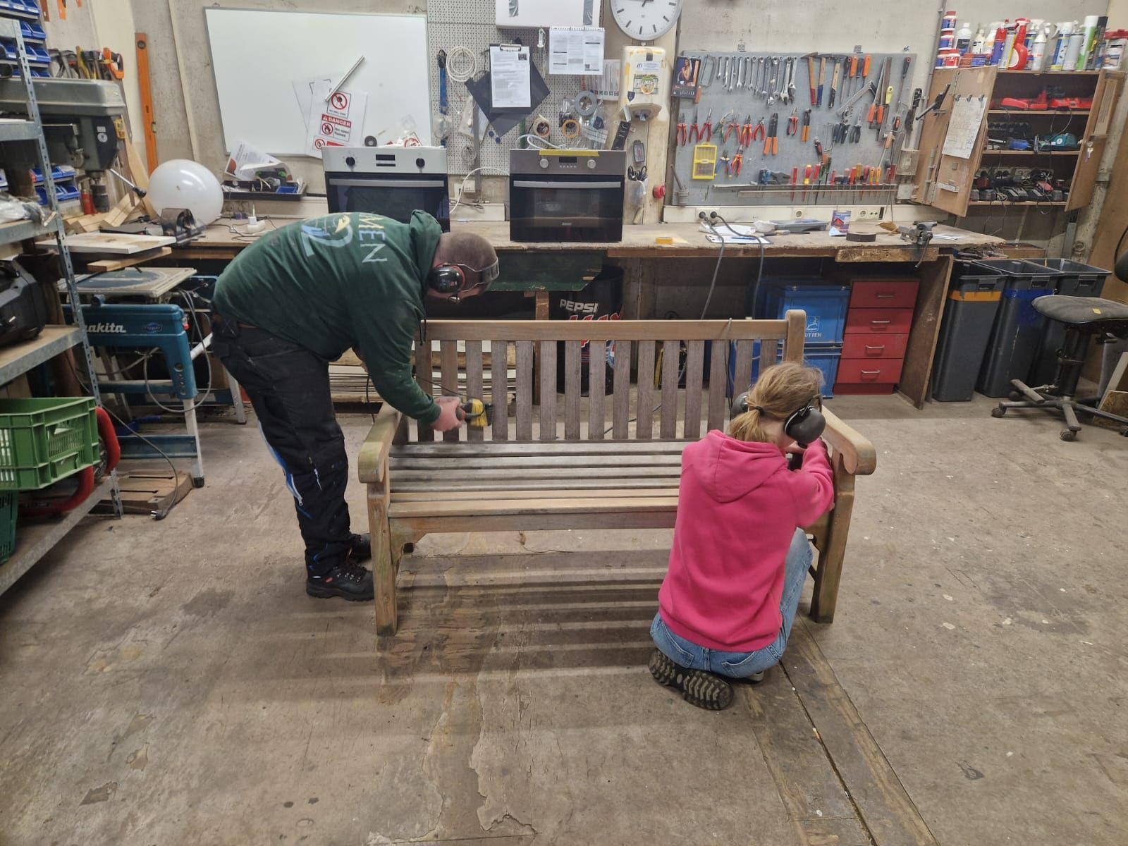 Een man en een meisje werken op een houten bank in een werkplaats. Dagbesteding Samen102