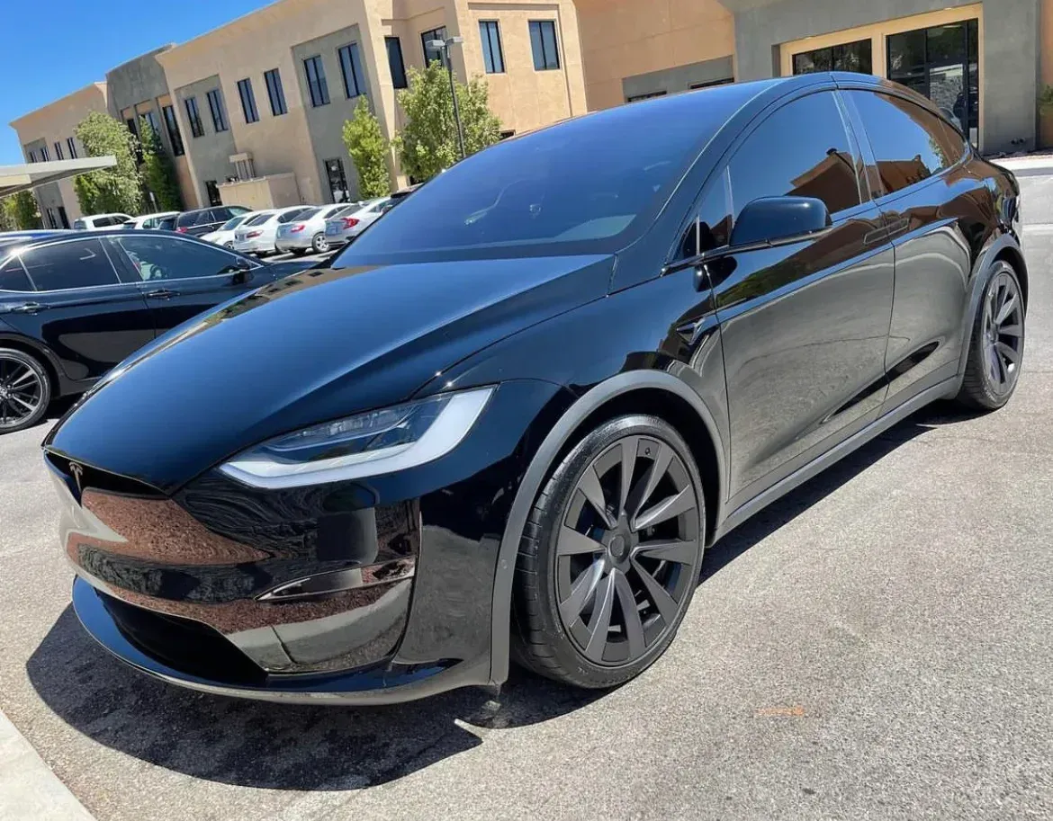 A black tesla model x is parked in front of a building.