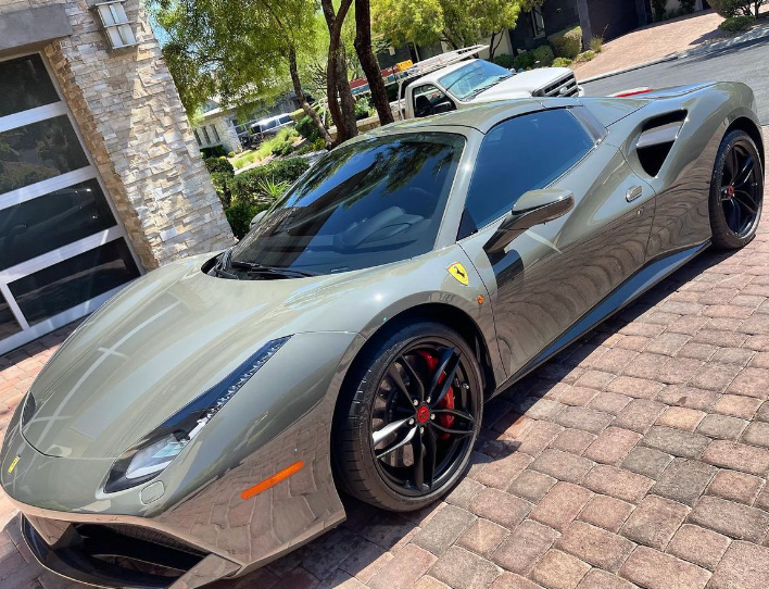 A ferrari 488 spider is parked on a brick driveway.