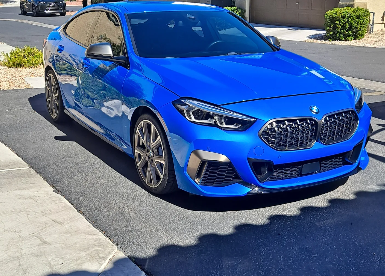 A blue bmw is parked on the side of the road