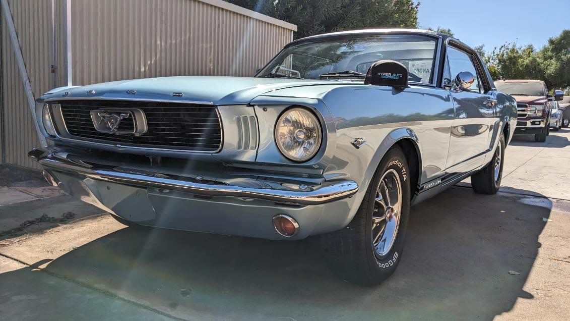 A blue ford mustang is parked in front of a building.