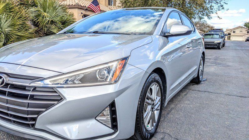 A silver hyundai elantra is parked on the side of the road.
