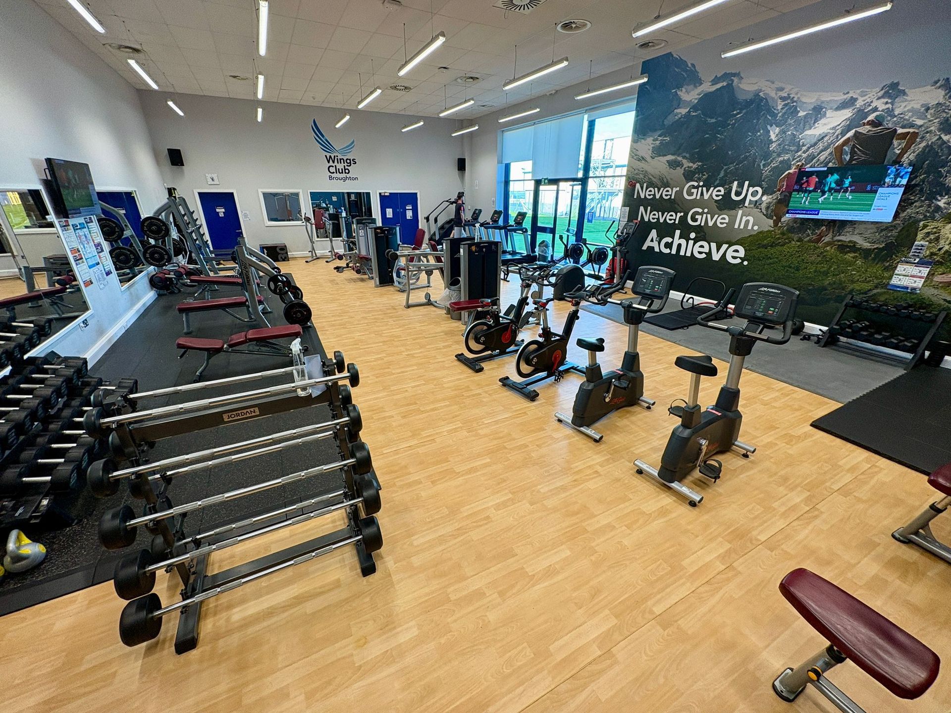 Gym interior with weights, cardio machines, and motivational wall art.