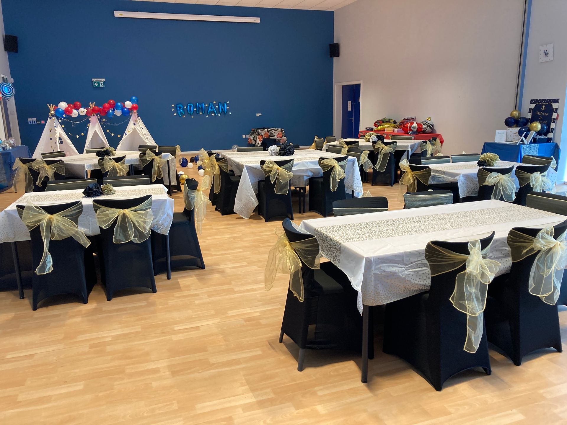 Party hall with decorated tables and chairs, blue walls, and teepees, ready for an event.