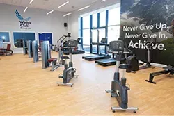 Gym interior with exercise machines: treadmills, bikes, and weight machines. Motivational poster:
