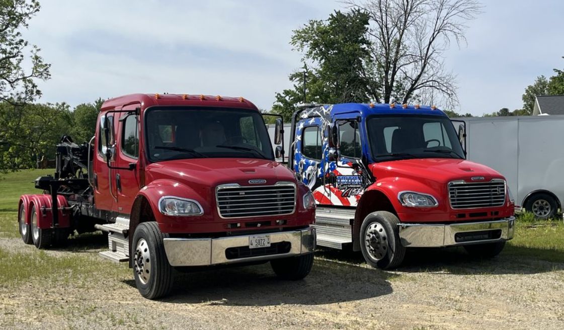 Two red and one blue/red freightliner trucks parked outdoors.