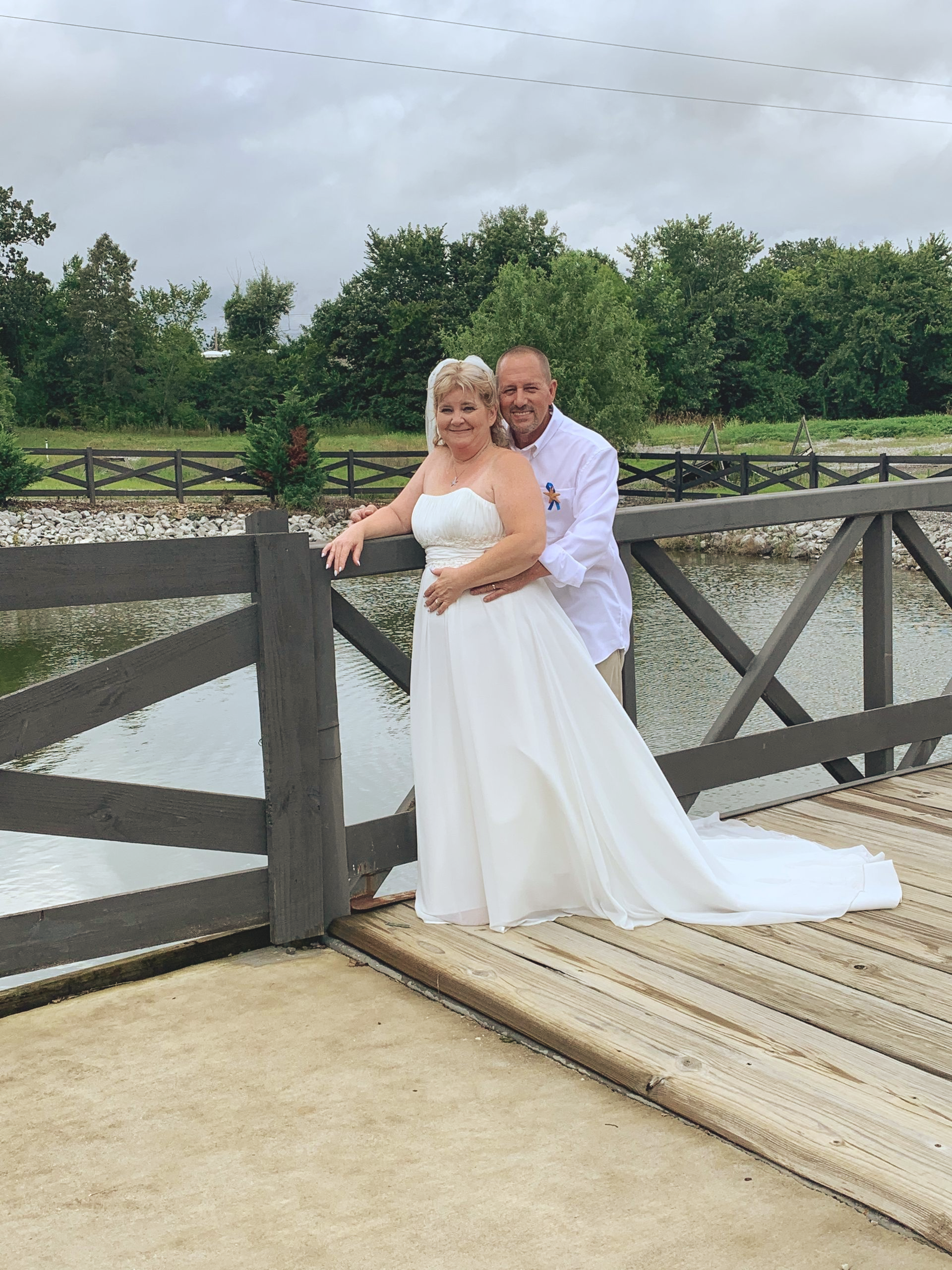 bride and groom embracing on bridge
