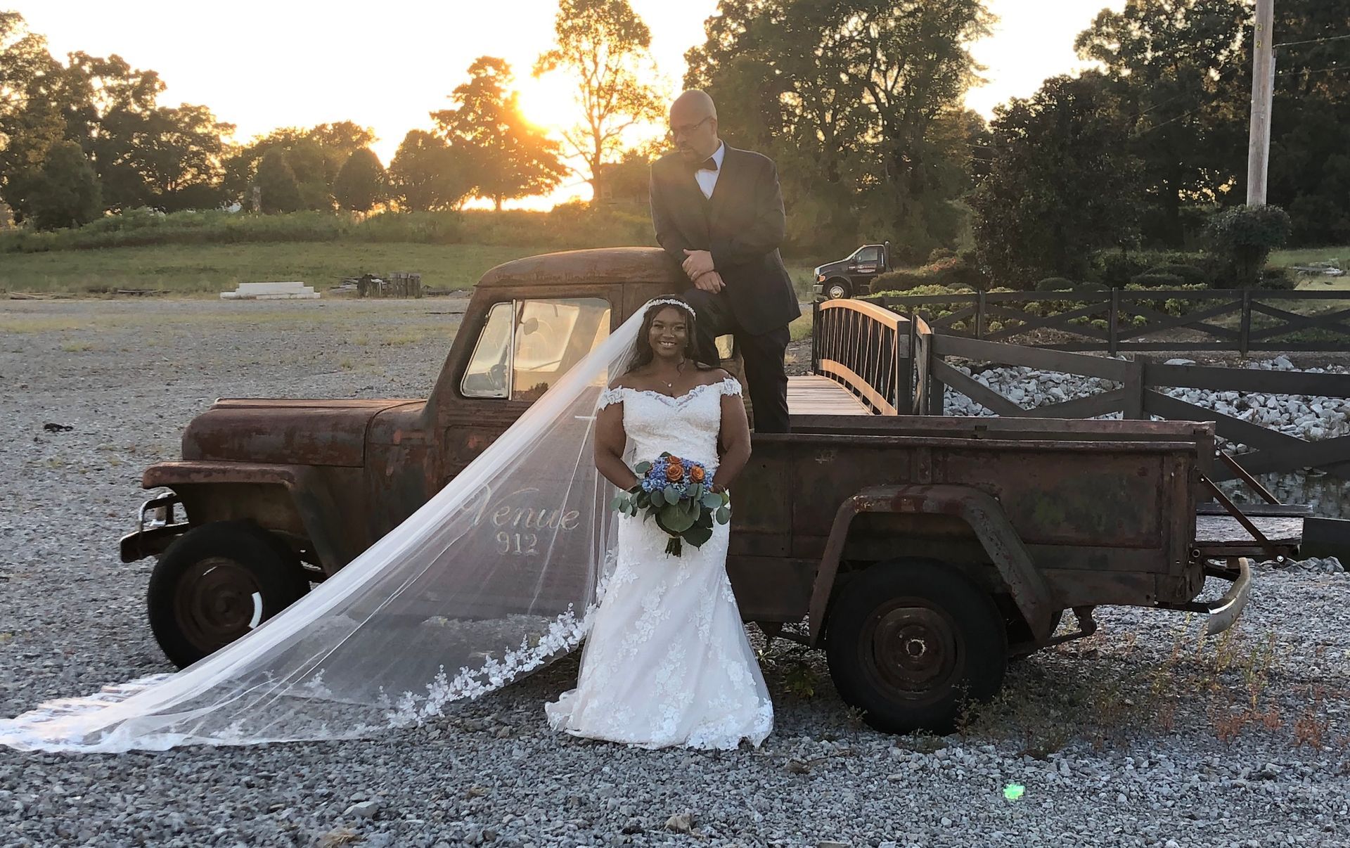 bride and groom posing on antique truck