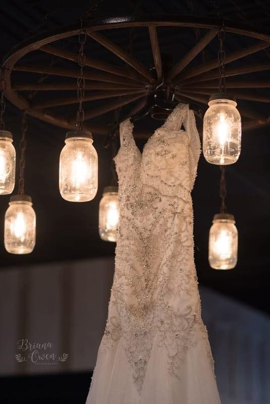 wedding gown hanging from chandelier with mason jars