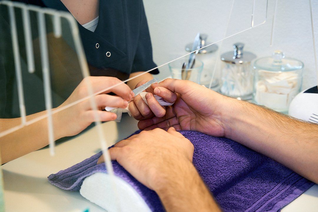 Ein Mann lässt sich von einer Kosmetikerin die Nägel machen.