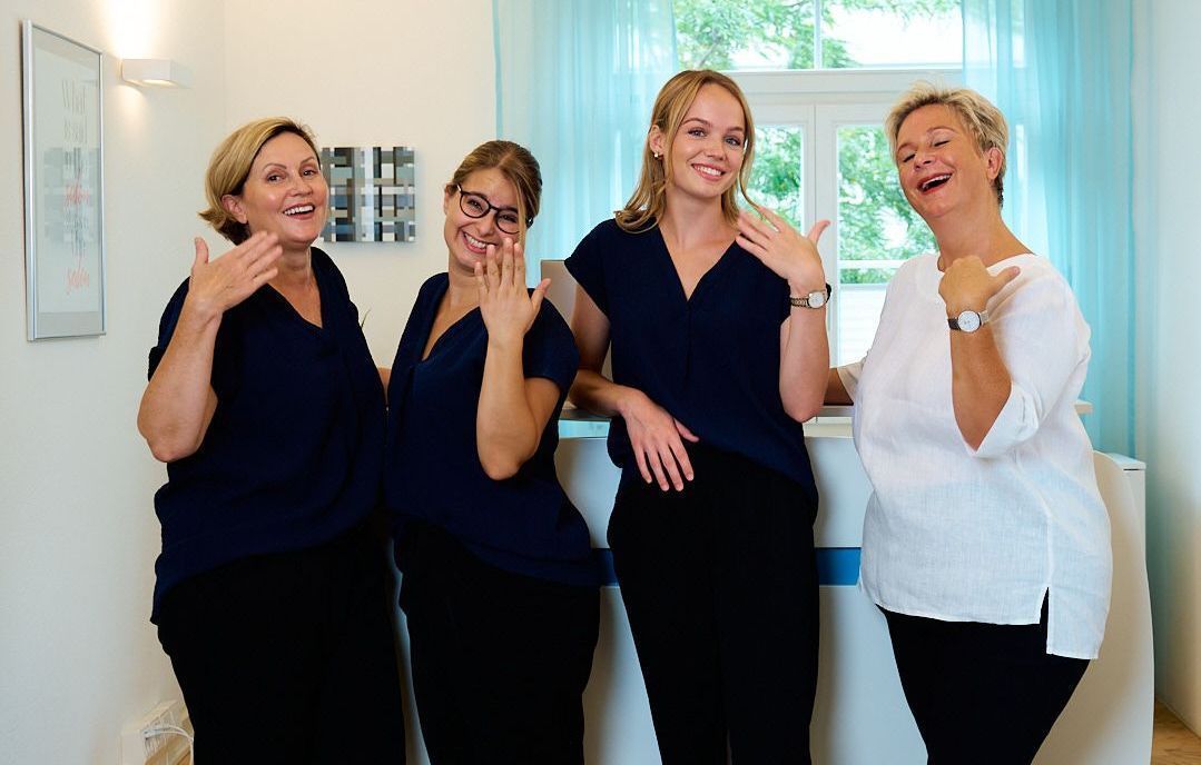 Vier Frauen posieren für ein Foto vor einer Theke und machen die Symbolik dass es heiss ist