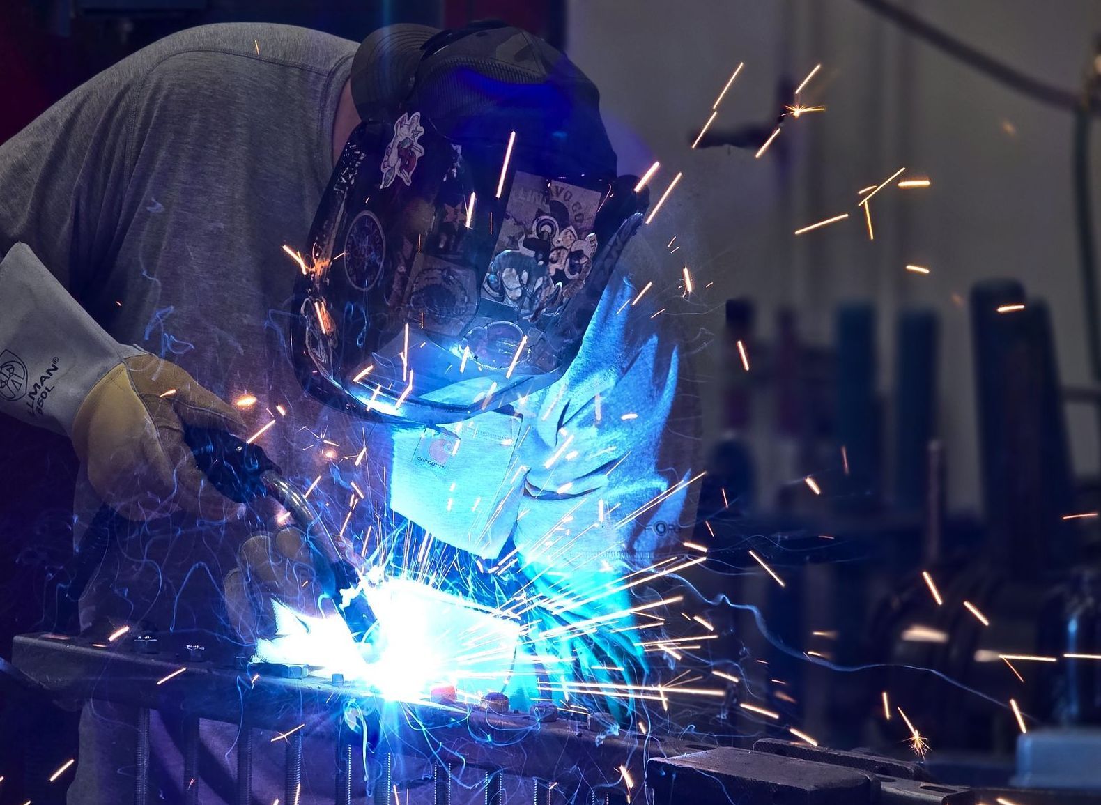 A man is welding a piece of metal in a factory.