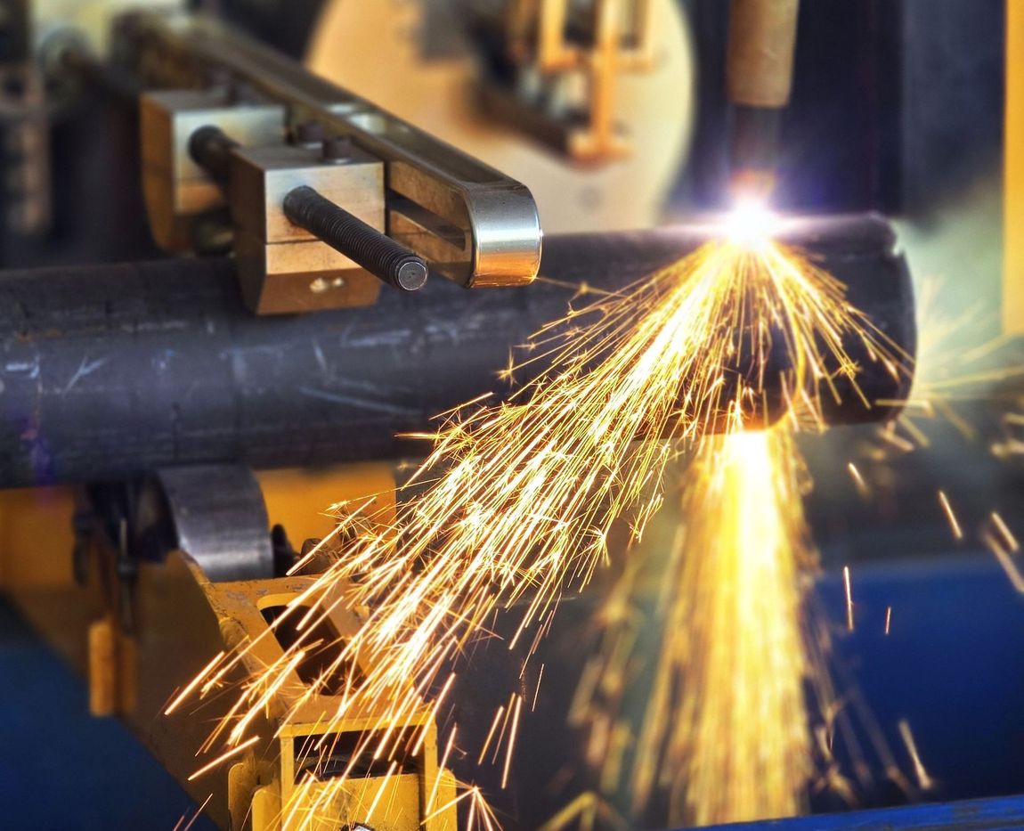 A machine is cutting a metal pipe with sparks coming out of it