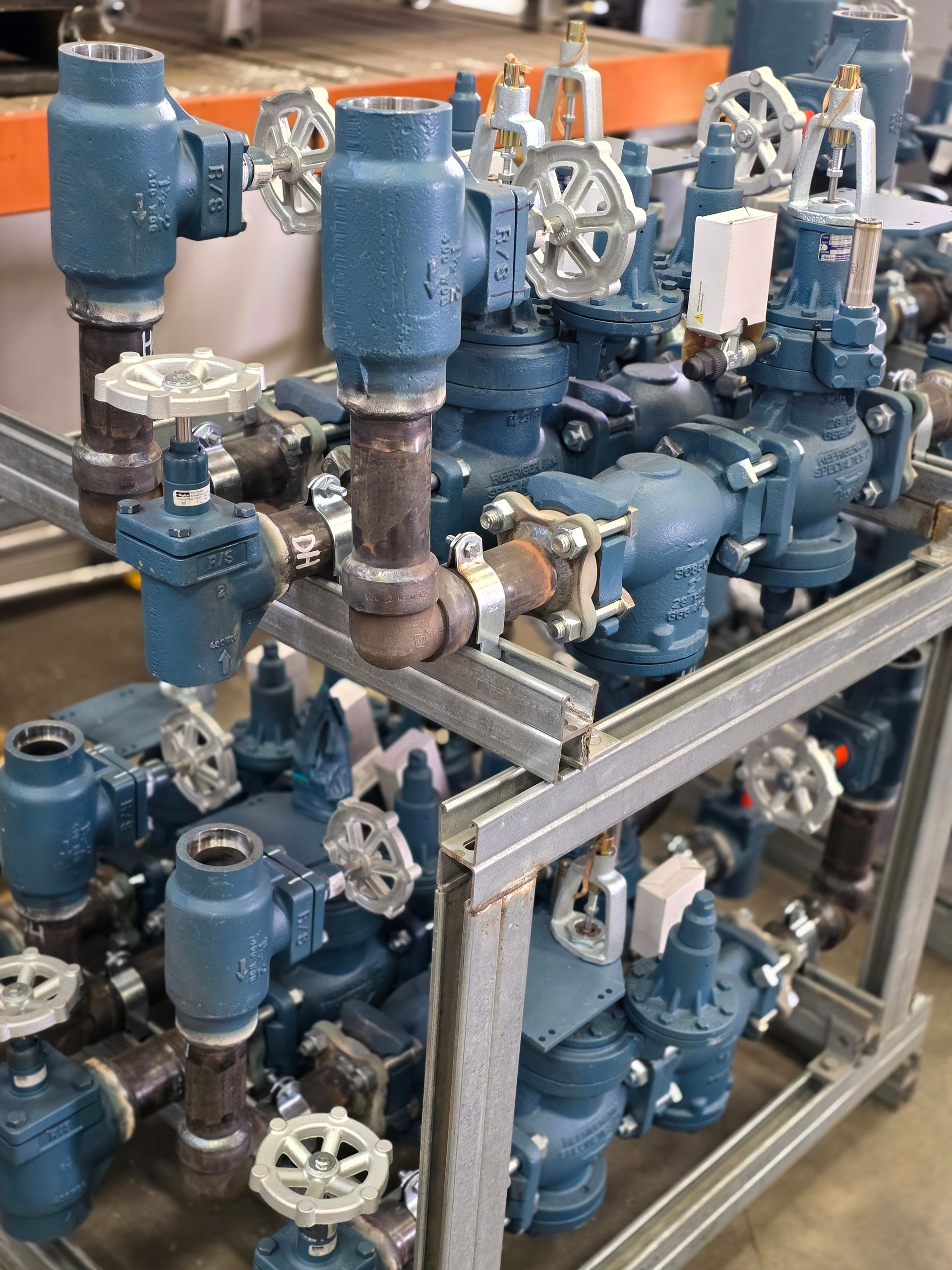 Complex system of blue pipes, valves, and fittings on a metal frame.