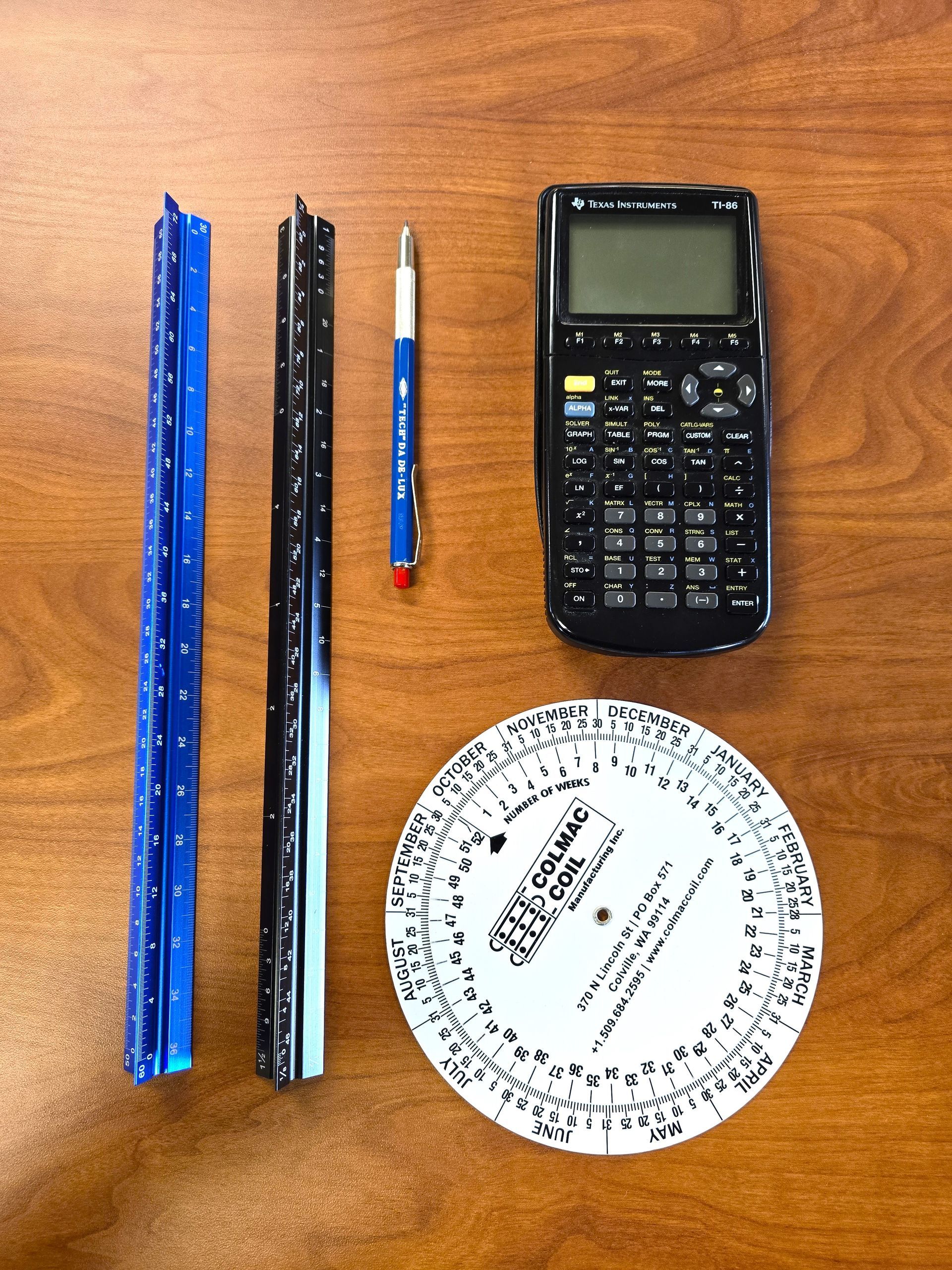 A calculator and a ruler are on a wooden table