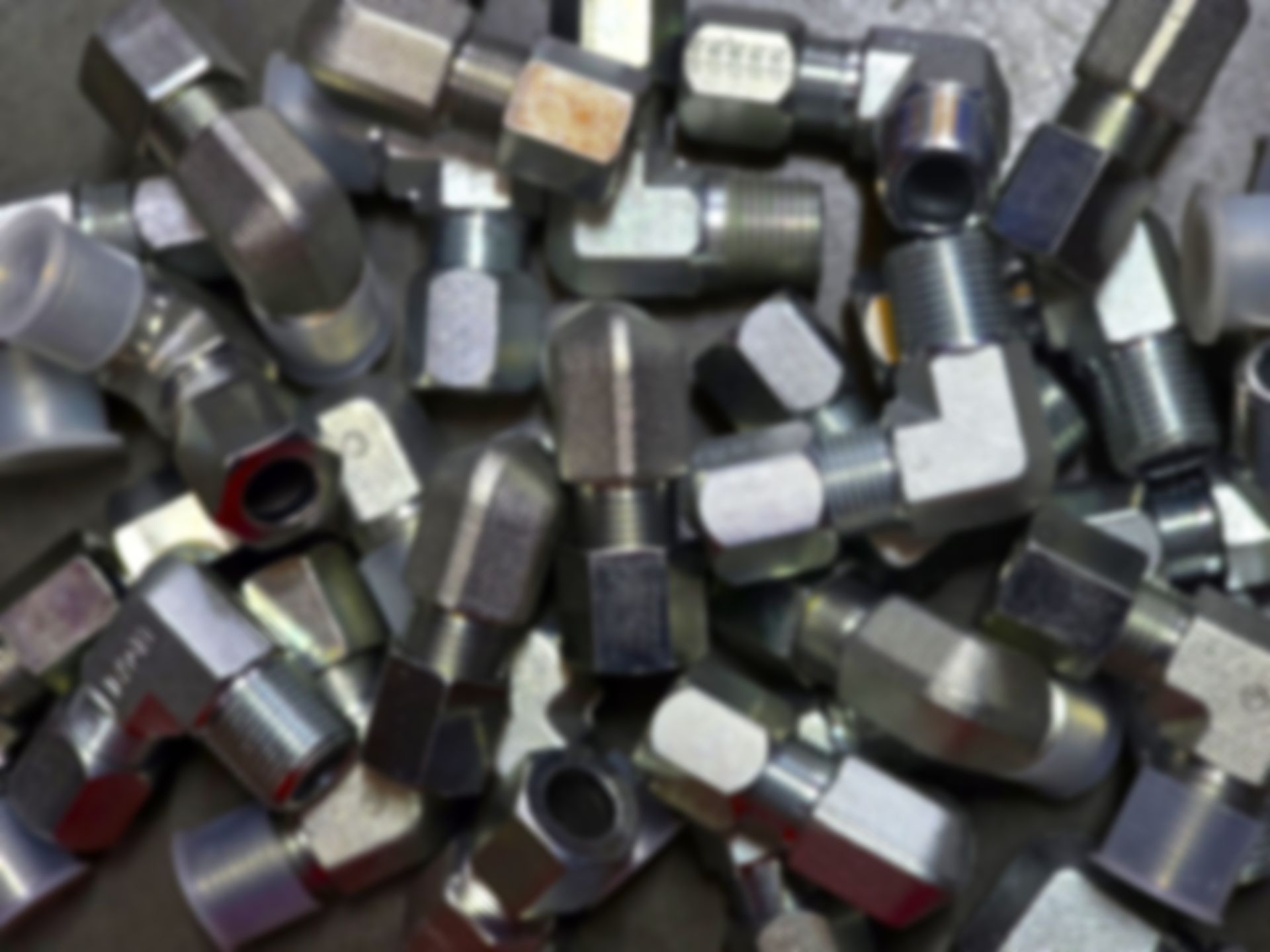 Pile of shiny, silver metal hydraulic fittings of various angles.