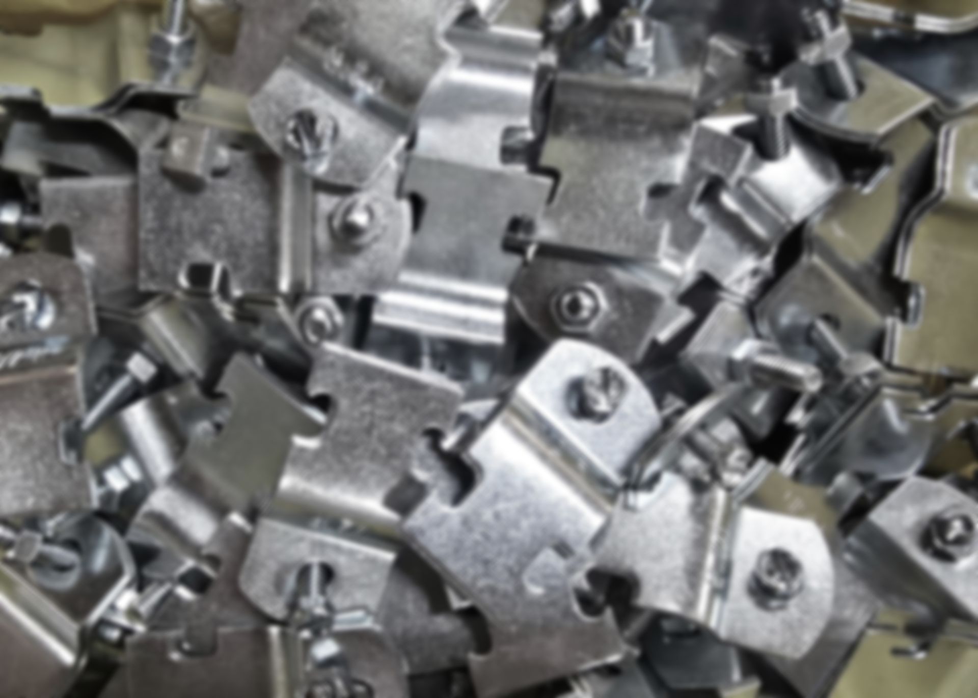 Pile of shiny metal clips with screws, stacked closely together