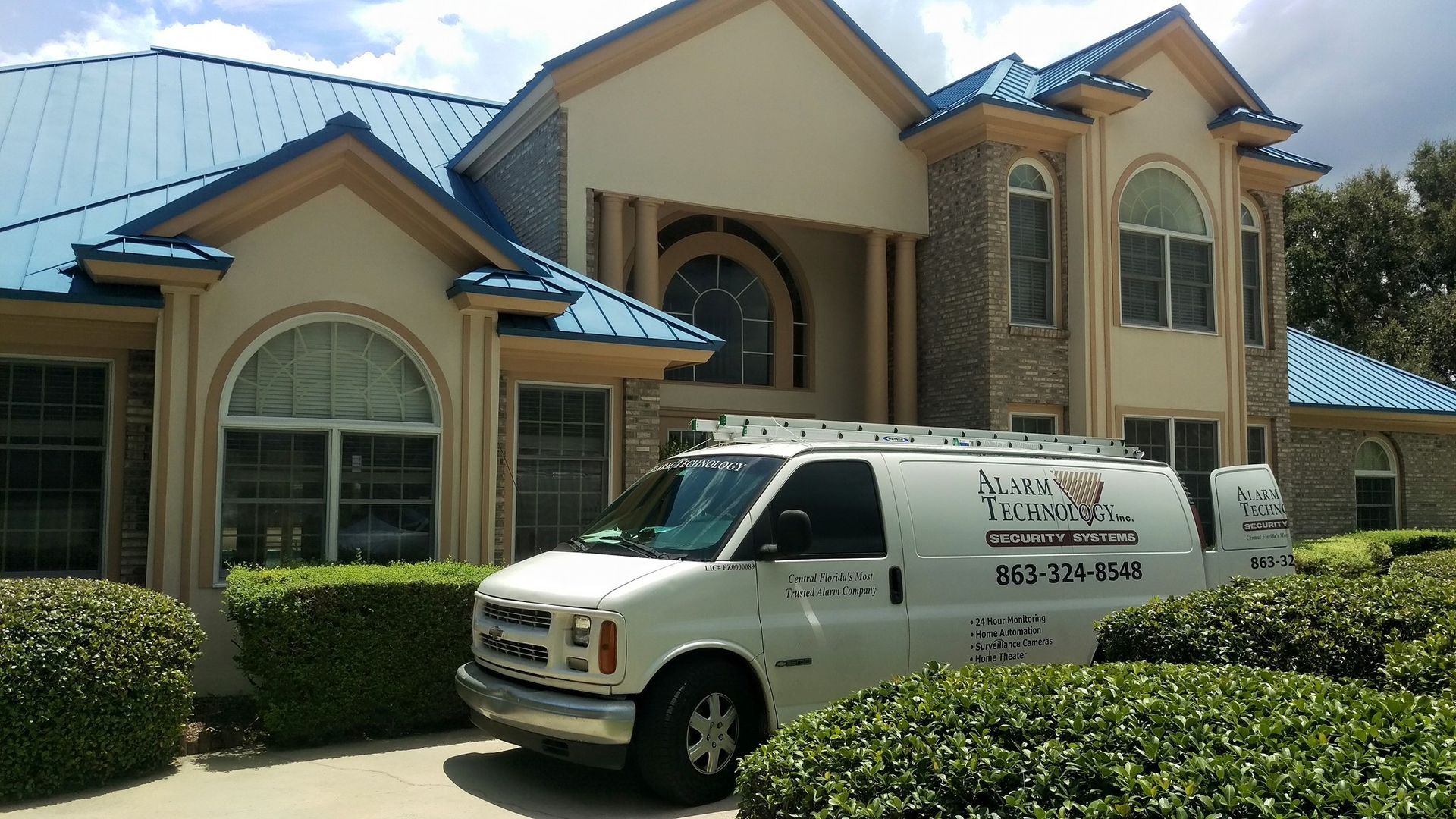 A white van is parked in front of a large house