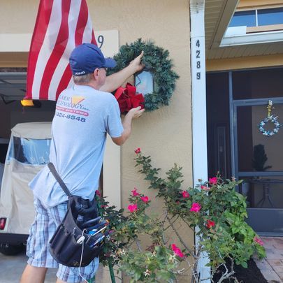 A man hanging a wreath on the side of a house