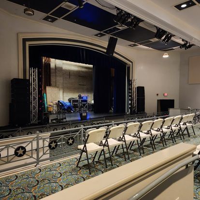 A large auditorium with rows of folding chairs in front of a stage.