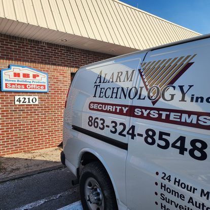 A white van for alarm technology inc. is parked in front of a brick building