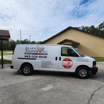 A white van for alarm technology is parked in front of a building