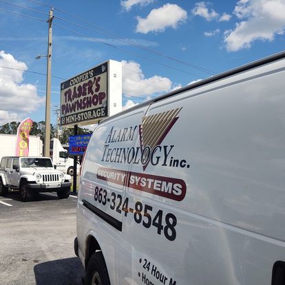 A white van is parked in front of a sign for trader 's pawnshop.