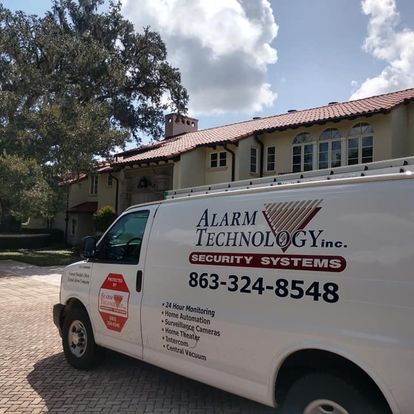 A white van from alarm technology inc. is parked in front of a house