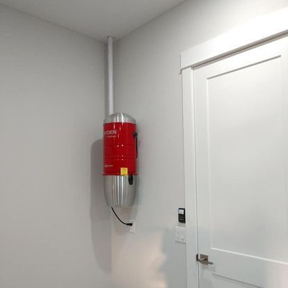 A red vacuum cleaner is hanging on the wall next to a white door.