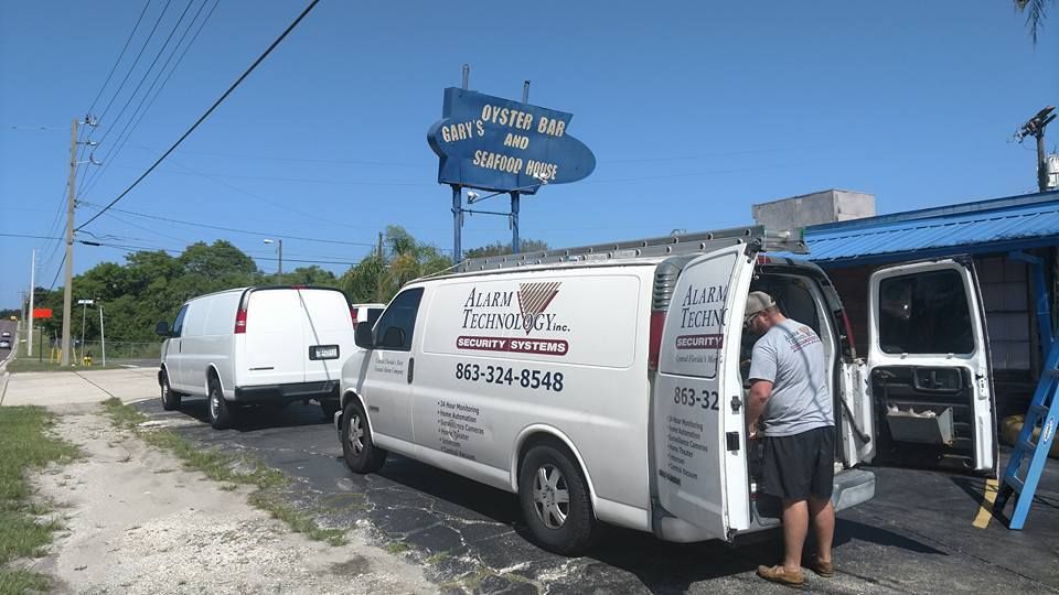 A man is standing next to a white van that says ' a & a ' on the side.